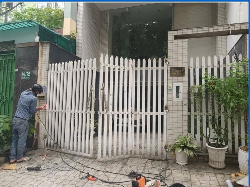 Thợ đang căn chỉnh và hàn bản lề cửa cổng sắt bị xệ tại Bình Thạnh